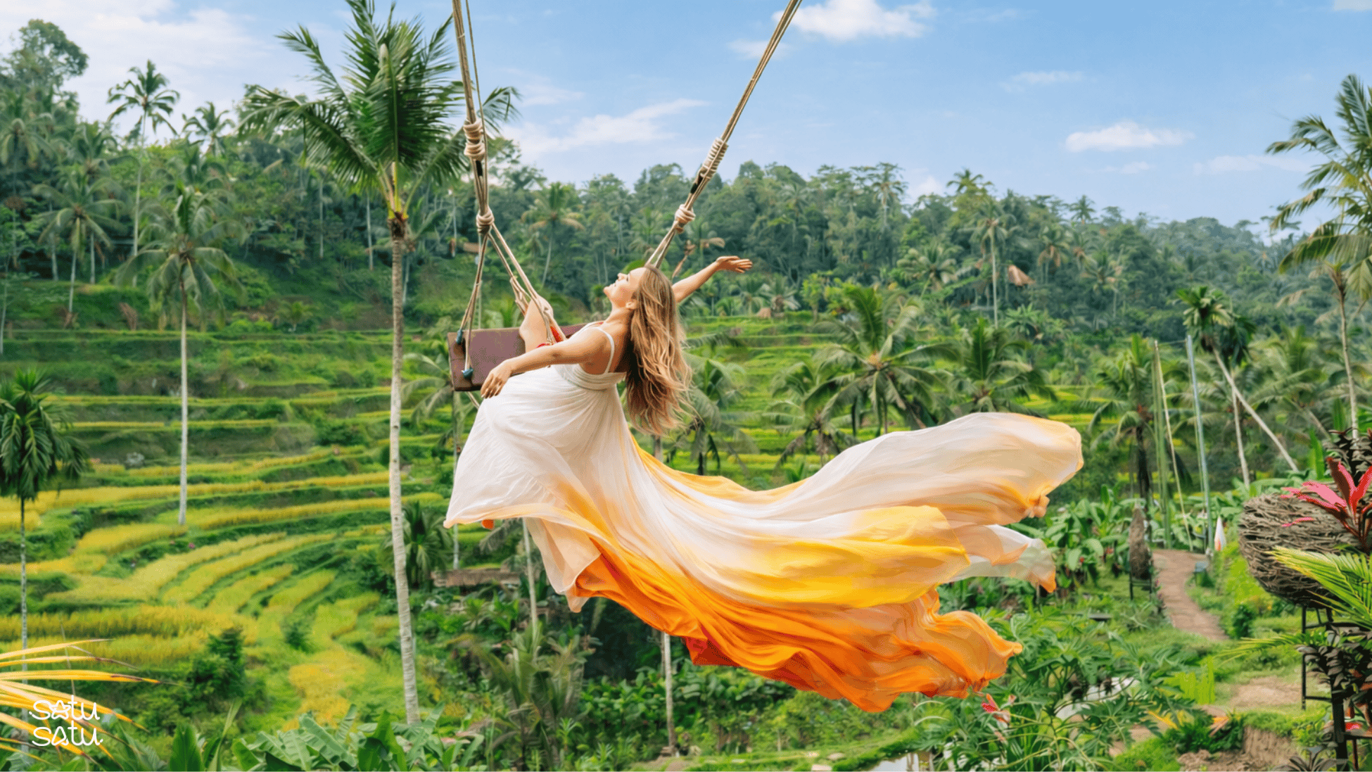 Woman enjoying Bali swing above rice terraces in Ubud surrounded by tropical landscape.