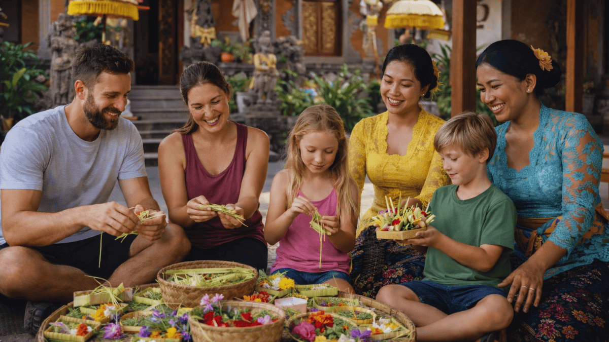 Tourists learning to make canang sari, traditional Balinese offerings, with local women in a temple courtyard in Bali.