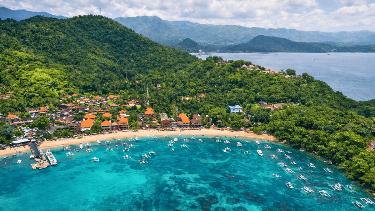 Aerial view of Blue Lagoon Beach in Padang Bai, Bali with turquoise water and boats along the shore.