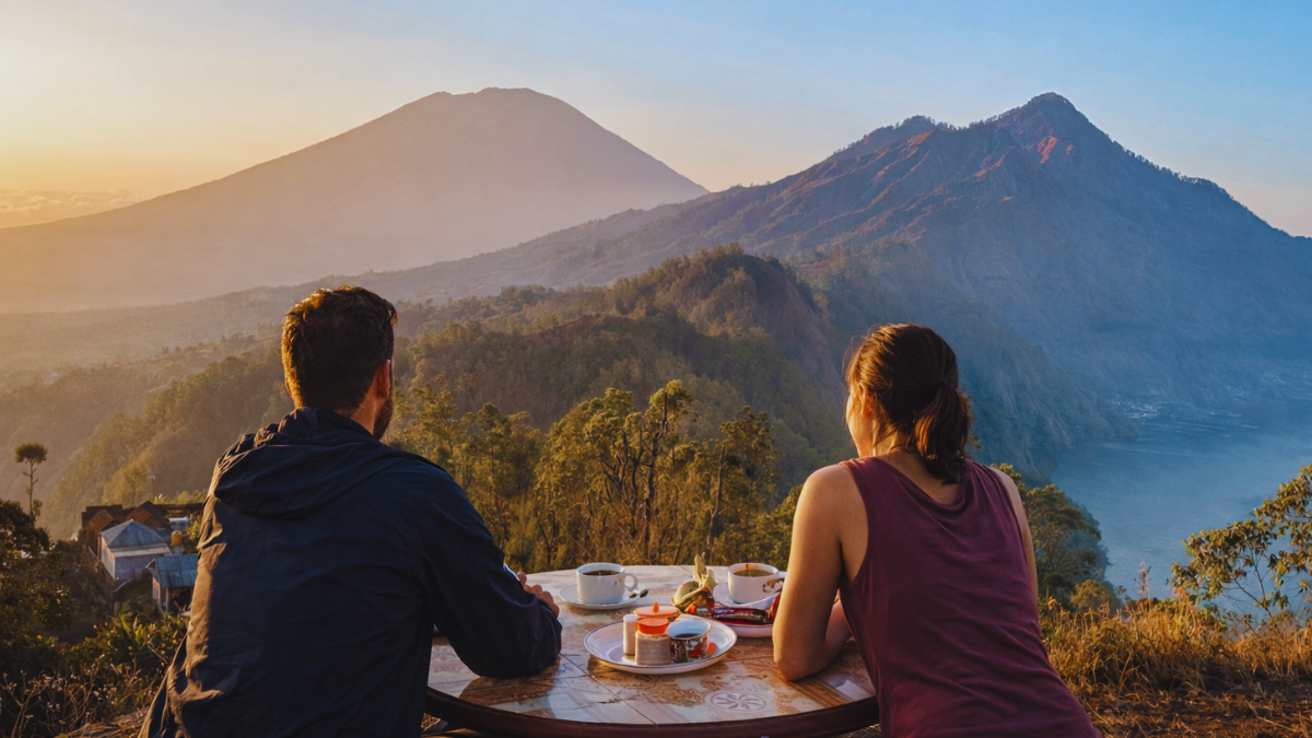 Two hikers enjoying a scenic mountain view after hiking Mount Batukaru in Bali with sunrise light and lake in the background.