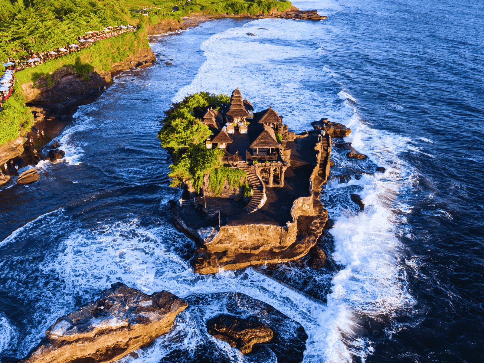 Aerial view of Tanah Lot Temple surrounded by ocean waves on Bali’s southwest coast.