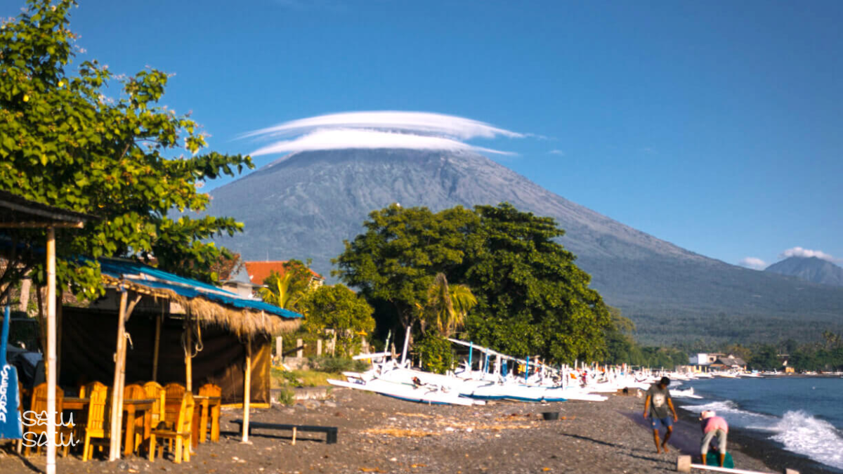 Amed Beach in Bali with traditional fishing boats and Mount Agung volcano rising in the background