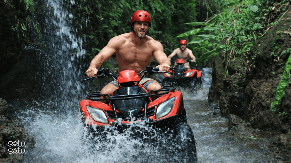 Traveler riding an ATV through a jungle trail and shallow river in Ubud, Bali.