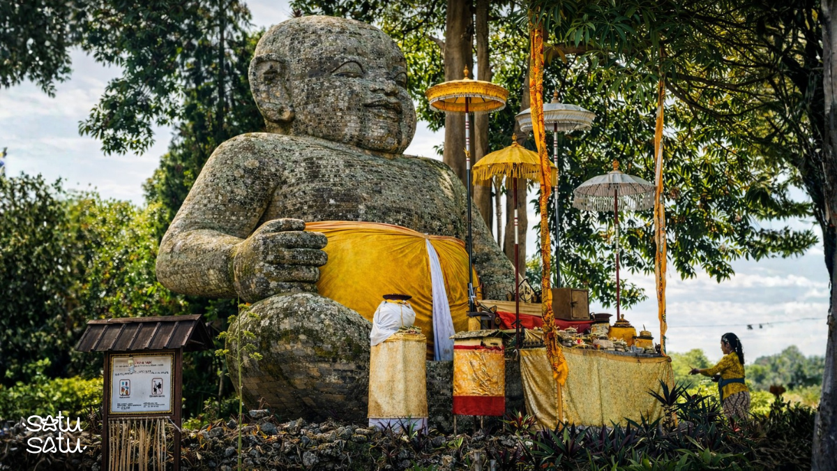 Bayi Sakah statue in Sukawati, Bali, a large stone baby sculpture surrounded by traditional Balinese offerings and ceremonial decorations.