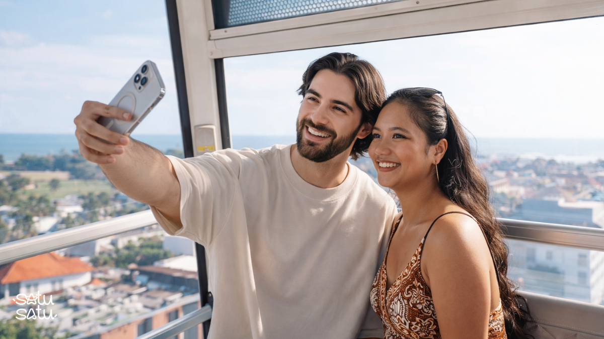 Couple taking a selfie inside a glass cabin on The Wheel Bali overlooking Canggu.