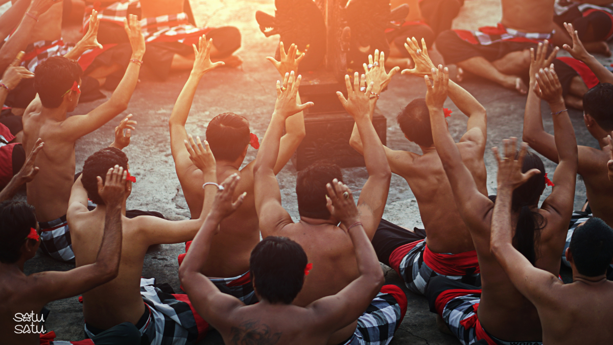 Balinese Kecak fire dance performance at Uluwatu Temple with traditional male dancers raising their hands during a cultural show