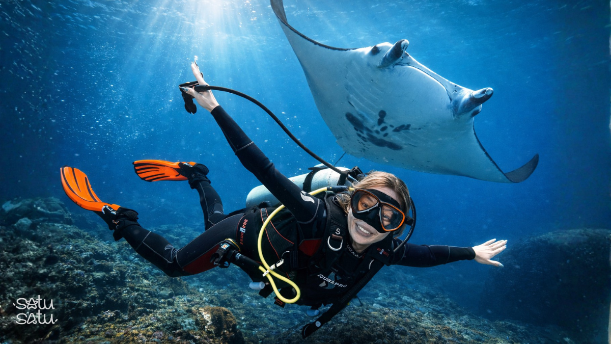 Scuba diver swimming with a manta ray at Manta Point in Nusa Penida, Bali.