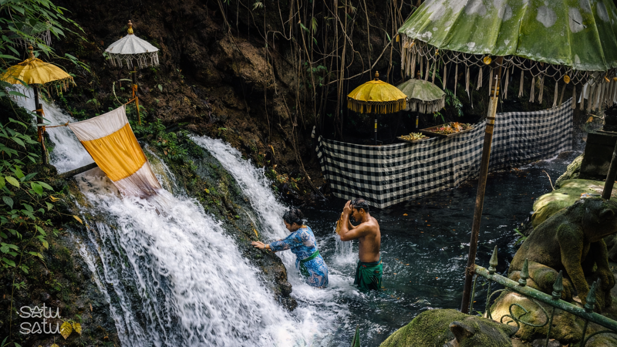 People performing melukat purification ritual at Pura Dalem Pingit Sebatu, Bali, under natural holy spring water surrounded by lush greenery.
