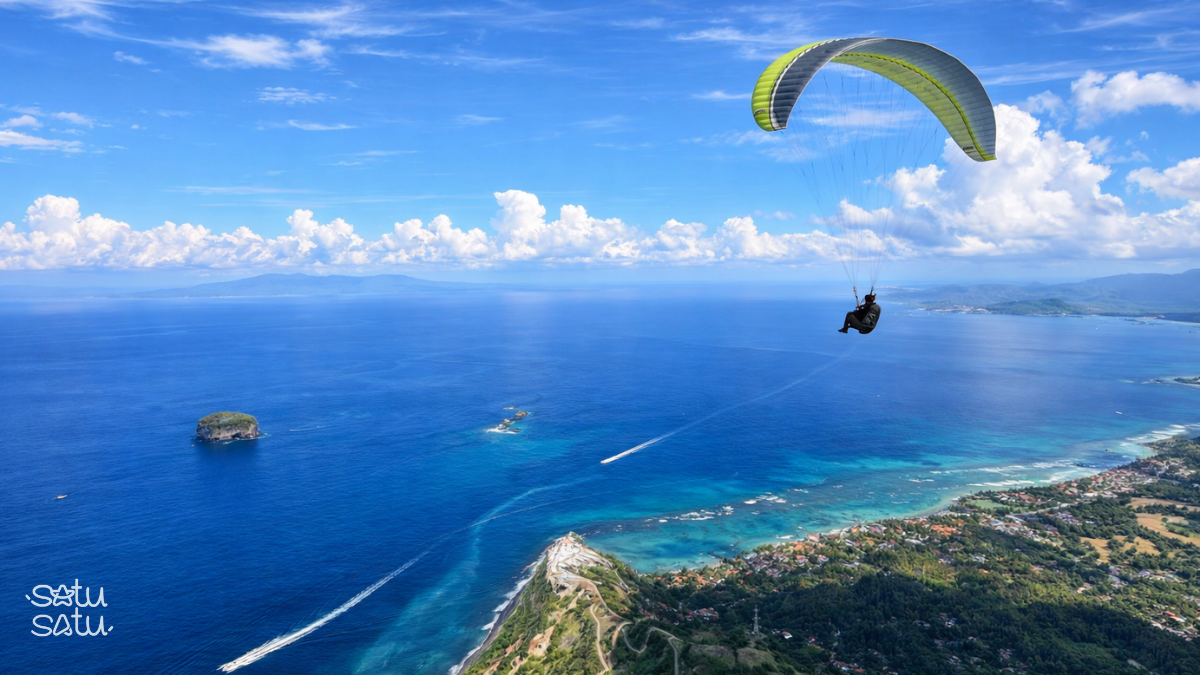 Paragliding over Timbis Beach Bali with panoramic aerial views of turquoise coastline and cliffs.