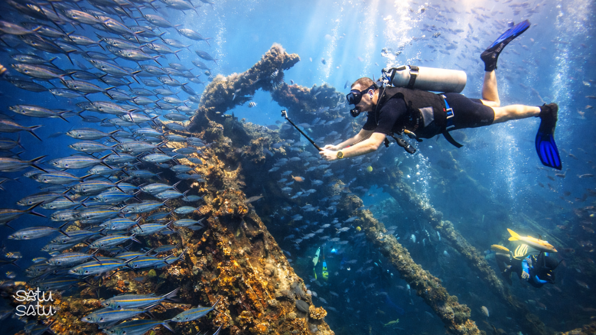 Scuba diver exploring the USAT Liberty shipwreck in Tulamben, Bali, surrounded by tropical fish.